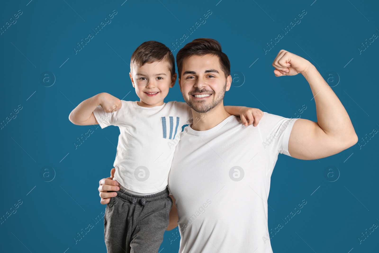 Photo of Portrait of sporty dad and his son on color background