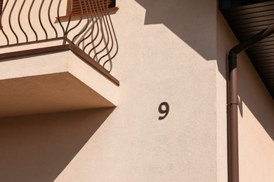 Photo of Number nine on beige house with balcony outdoors
