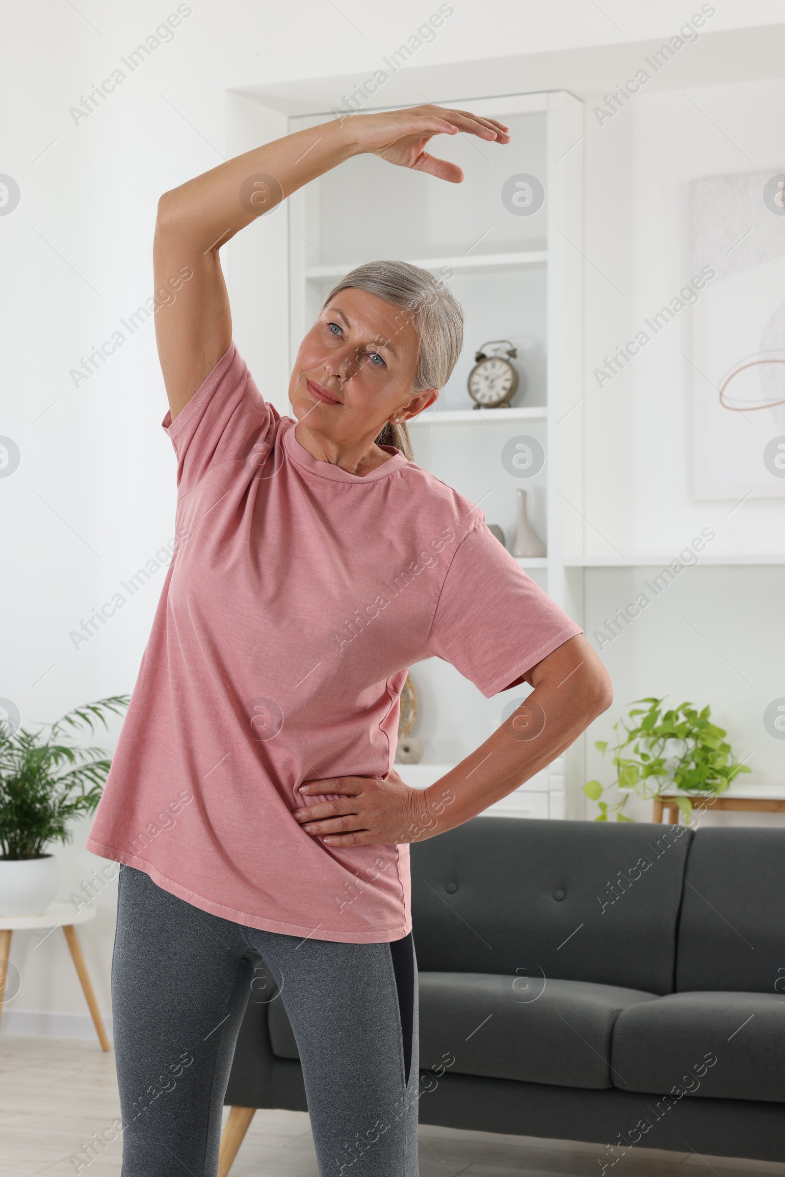 Photo of Senior woman in sportswear stretching at home