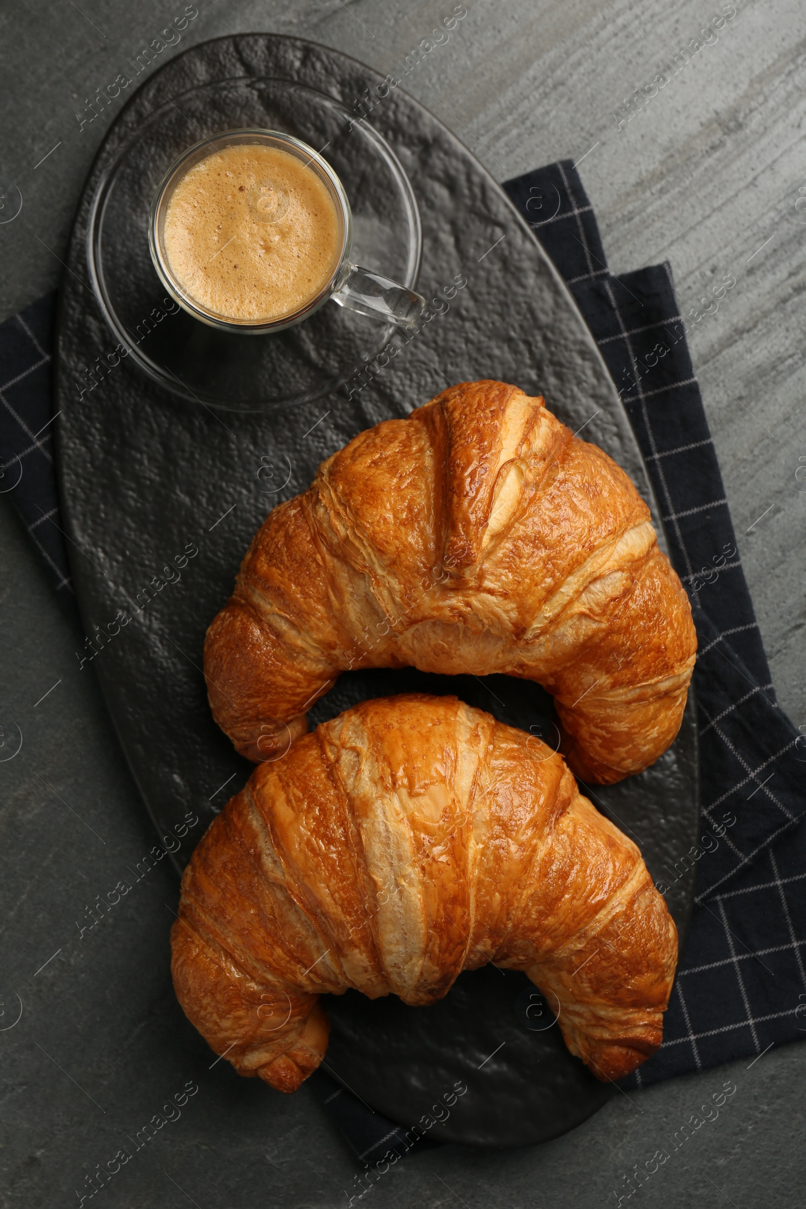 Photo of Delicious fresh croissants and cup of coffee on gray table, flat lay