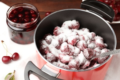 Photo of Pot with cherries and sugar on table, closeup. Making delicious jam