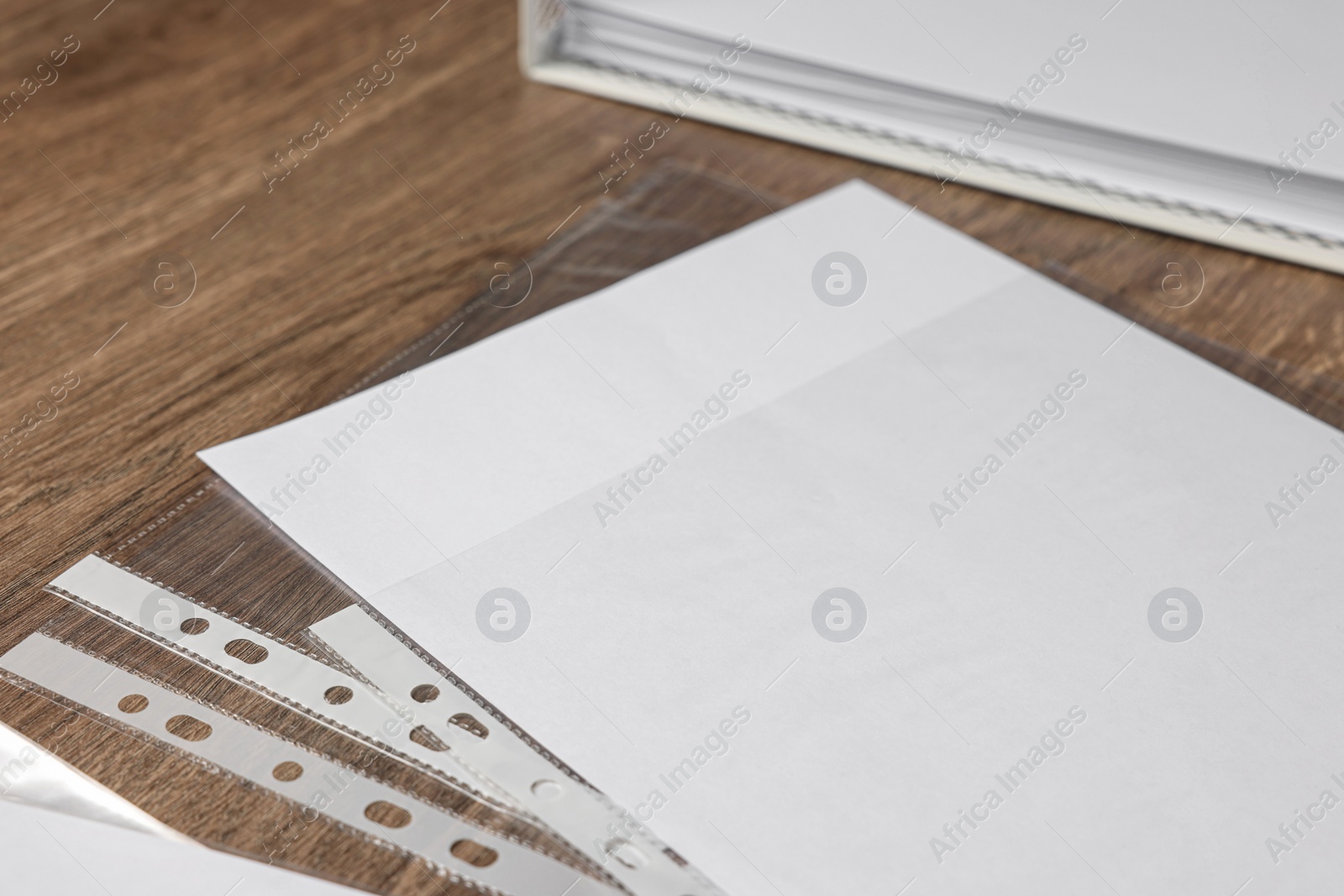 Photo of Punched pockets with paper sheet on wooden table, closeup