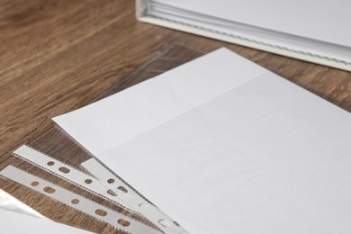 Punched pockets with paper sheet on wooden table, closeup