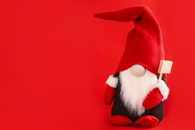 Photo of Cute Christmas gnome on red background. Space for text
