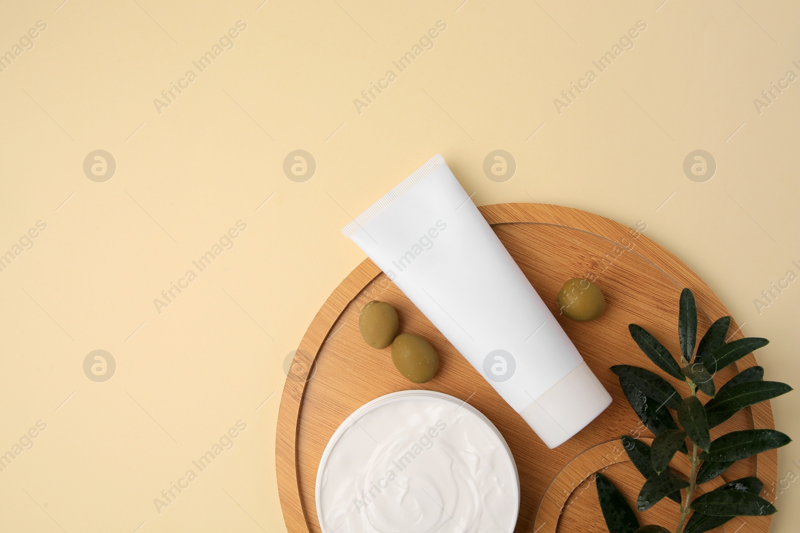 Photo of Natural cosmetic. Different olive creams and ingredient on beige background, top view. Space for text