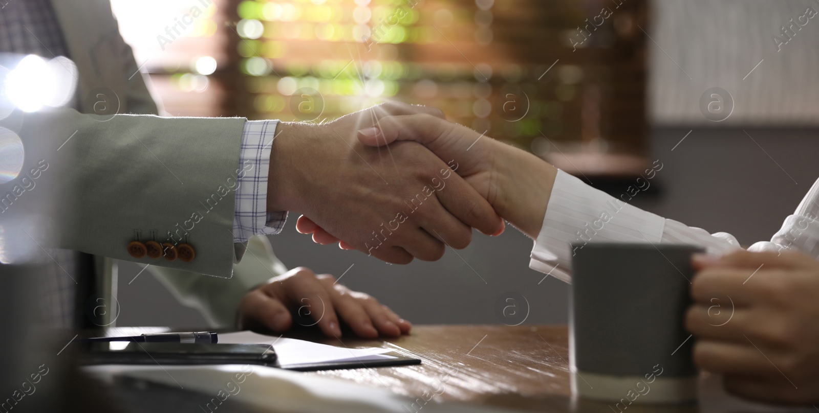 Image of Business partners shaking hands at table after meeting in office, closeup. Banner design