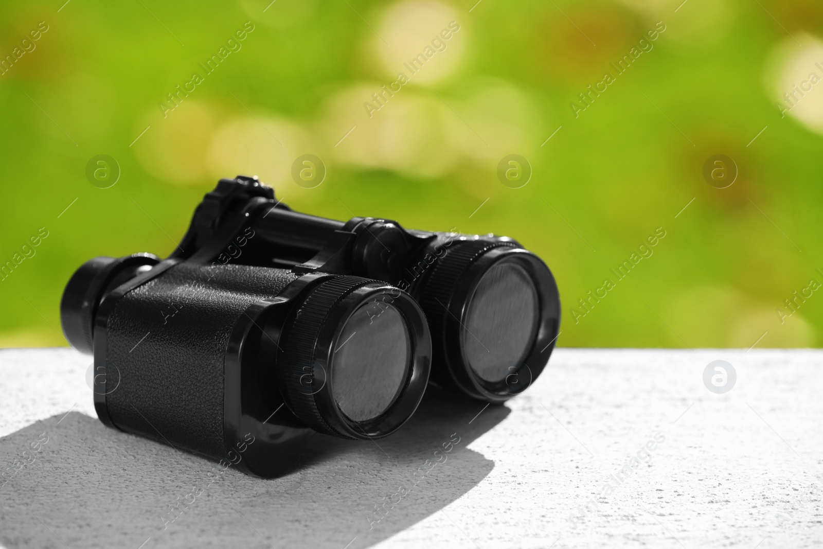Photo of Modern binoculars on stone surface outdoors, space for text