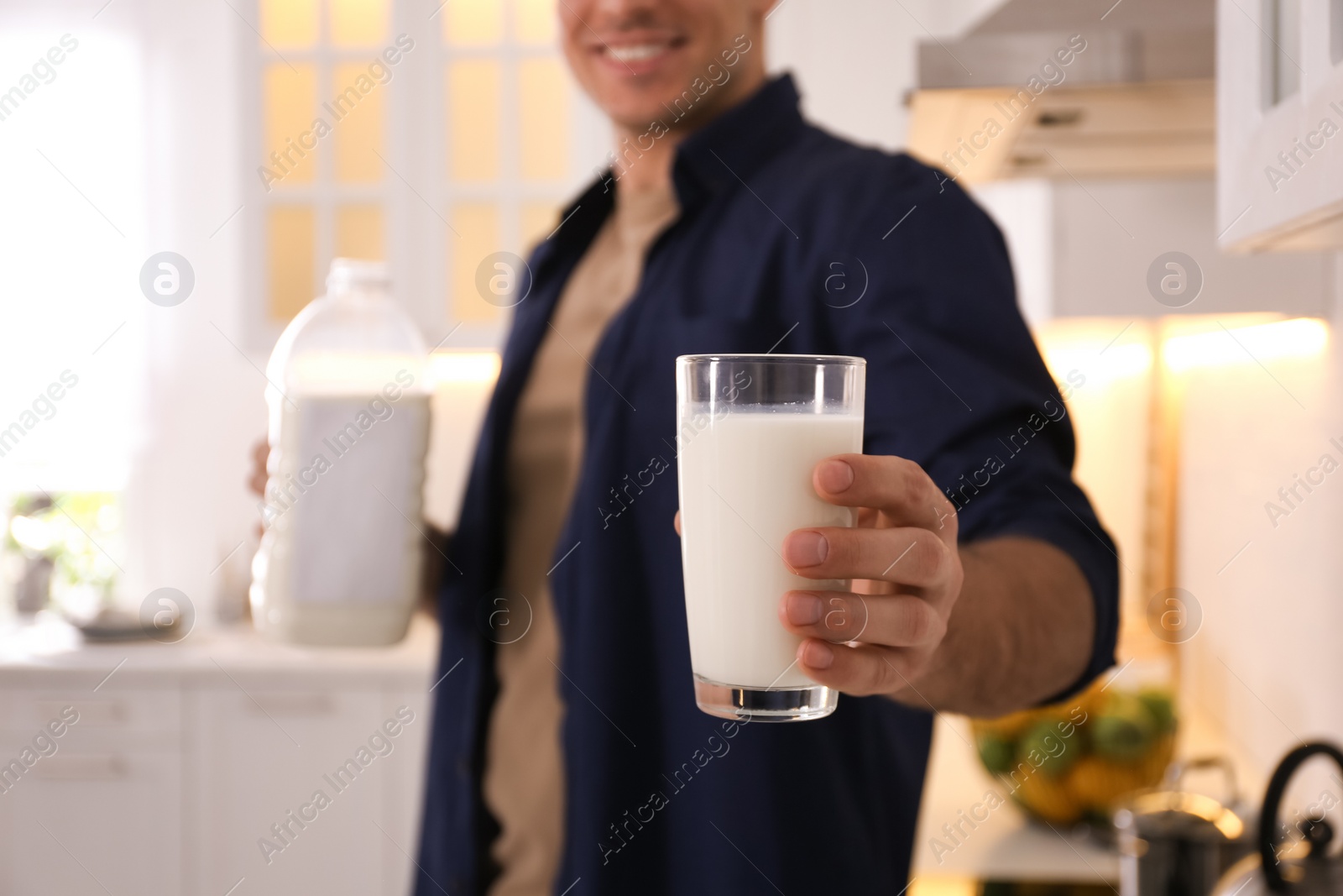 Photo of Man with glass and gallon bottle of milk in kitchen, closeup