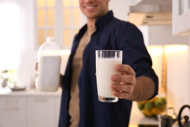 Man with glass and gallon bottle of milk in kitchen, closeup