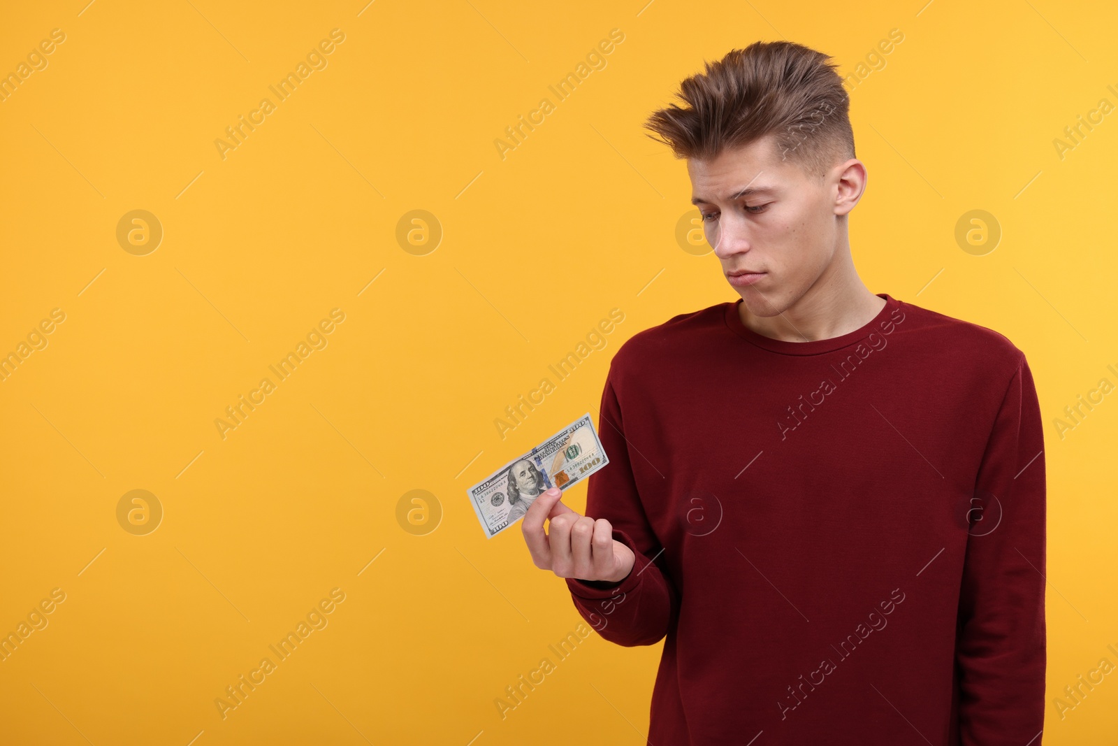 Photo of Upset man with dollar banknote on yellow background. Space for text