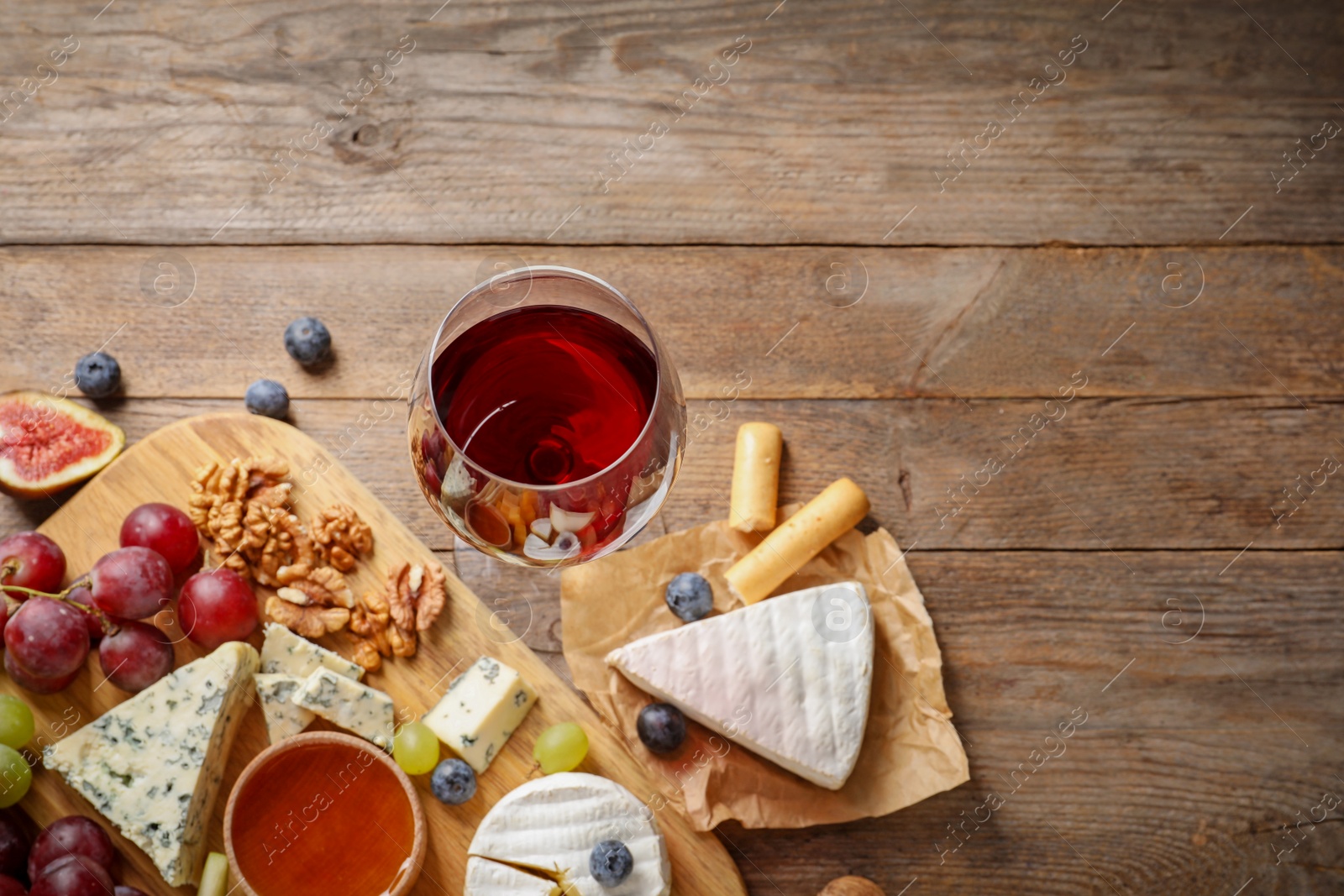 Photo of Composition with board of delicious cheese and snacks on wooden background, top view. Space for text