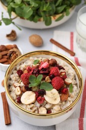 Delicious oatmeal with freeze dried berries, banana, nuts and mint on white table
