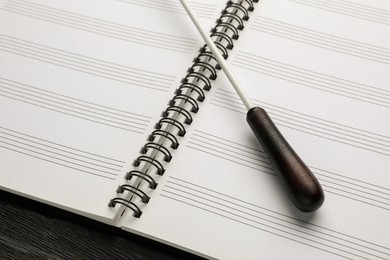 Photo of Conductor's baton and lead sheet on black wooden table