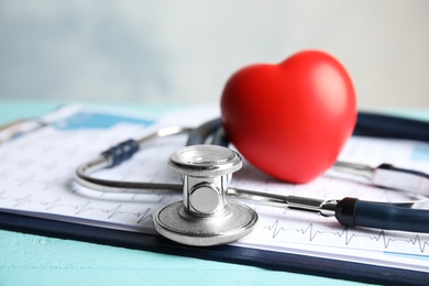 Stethoscope, red heart and cardiogram on table. Cardiology concept