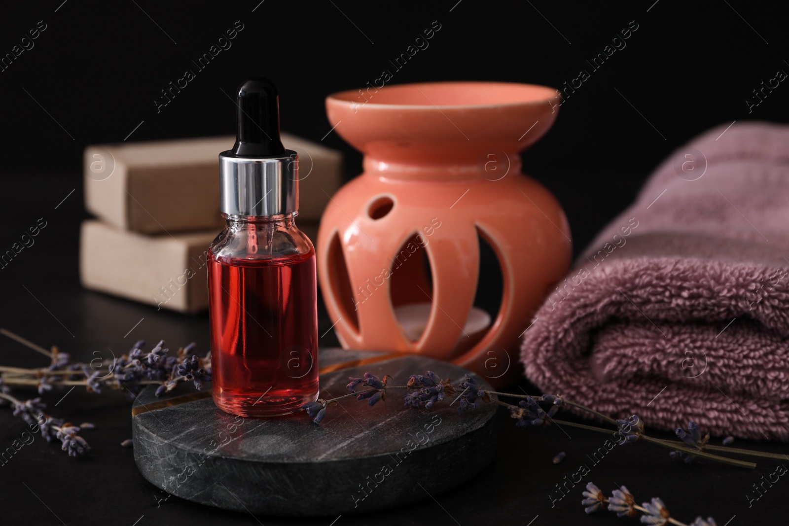 Photo of Lavender essential oil for aroma lamp on black table