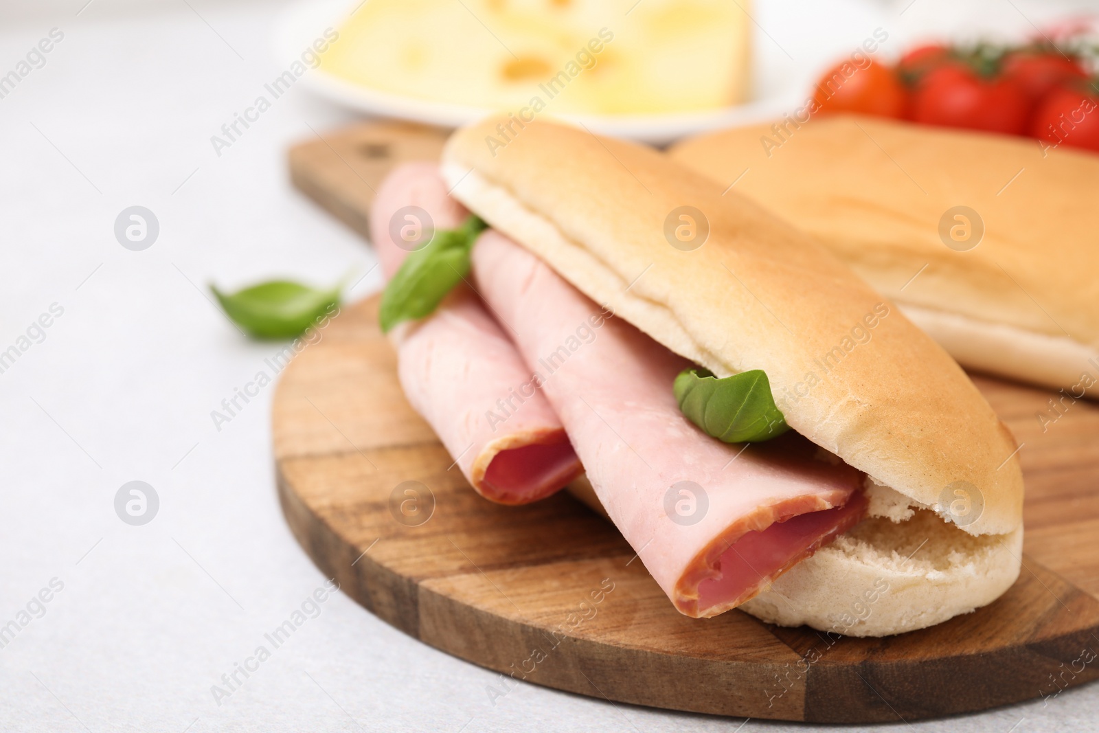 Photo of Delicious sandwich with ham and basil on white table, closeup