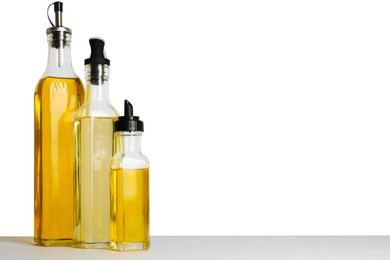 Photo of Bottles of different cooking oils on white background, space for text