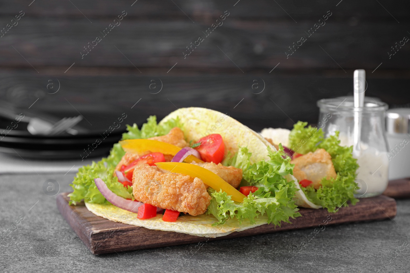 Photo of Delicious fish tacos served on grey table