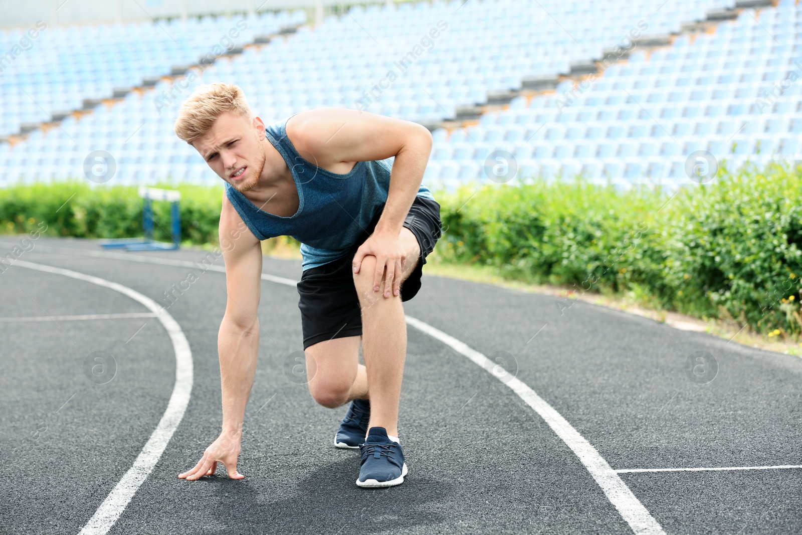 Photo of Man in sportswear suffering from knee pain at stadium