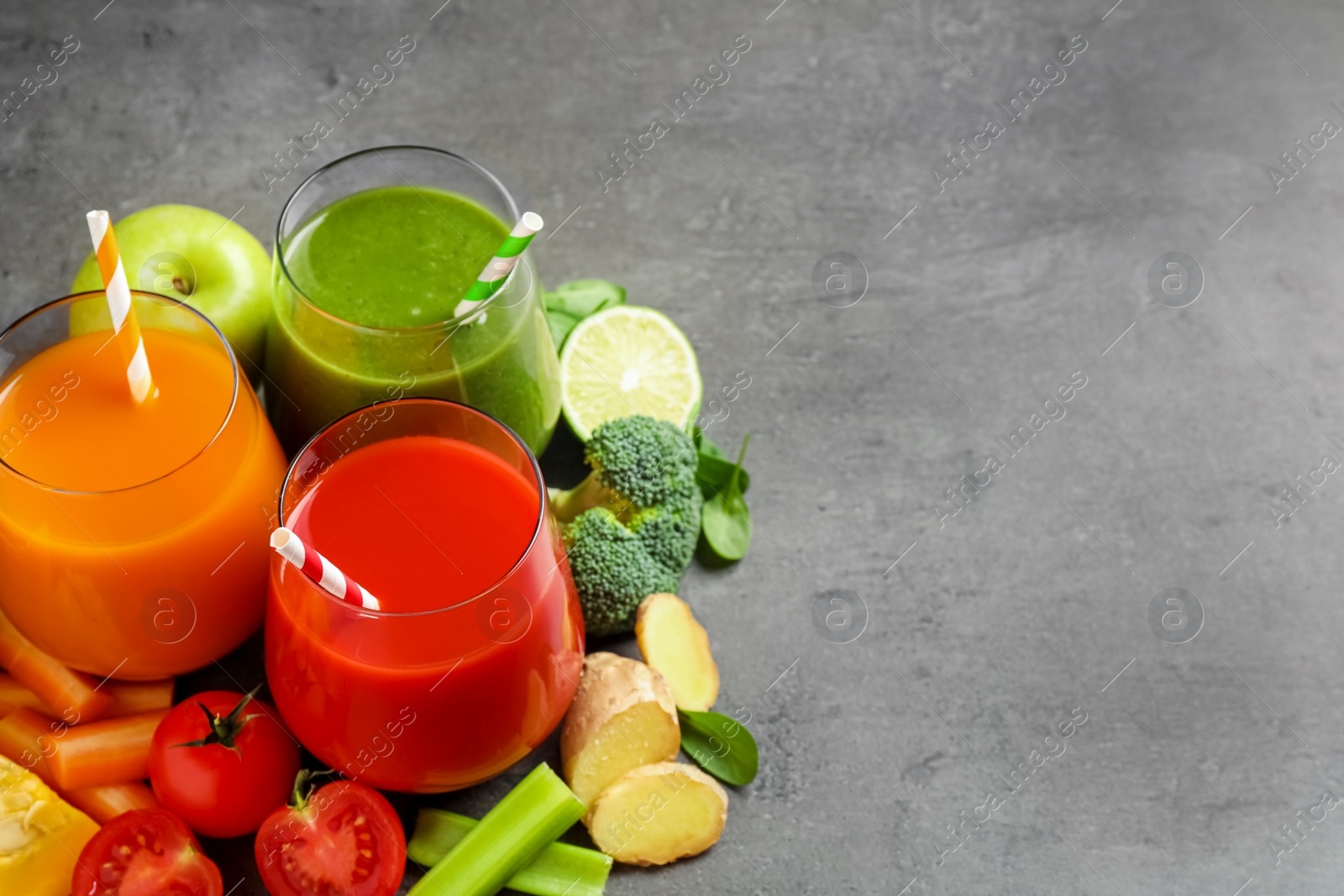 Photo of Different tasty juices and fresh ingredients on grey table. Space for text