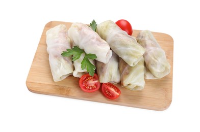 Photo of Wooden board with raw cabbage rolls, tomatoes and parsley isolated on white