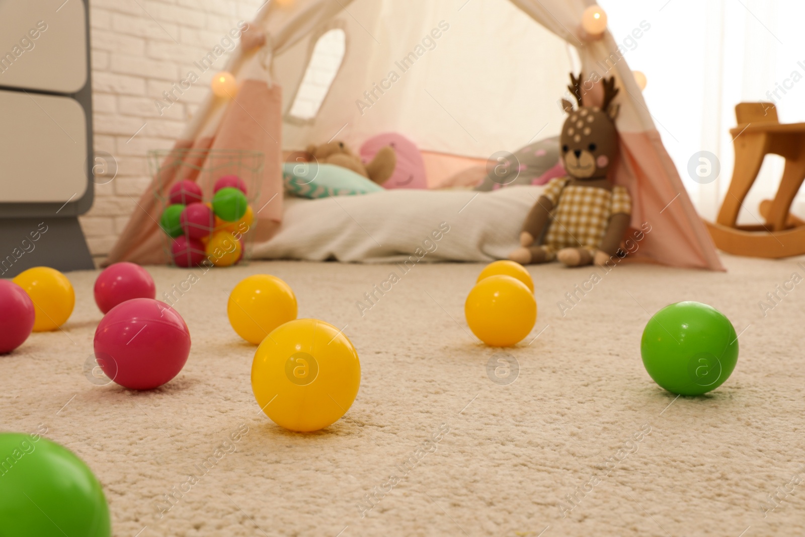 Photo of Bright toy balls near play tent on floor in child's room