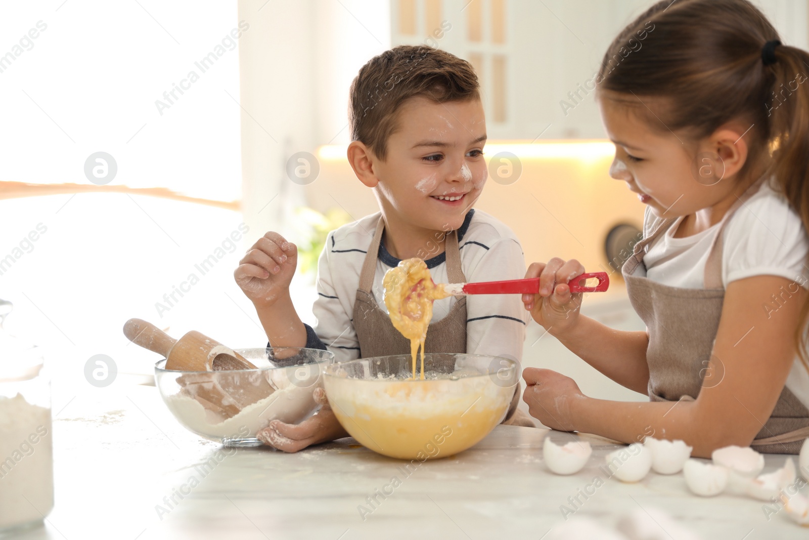 Photo of Cute little children cooking dough together in kitchen