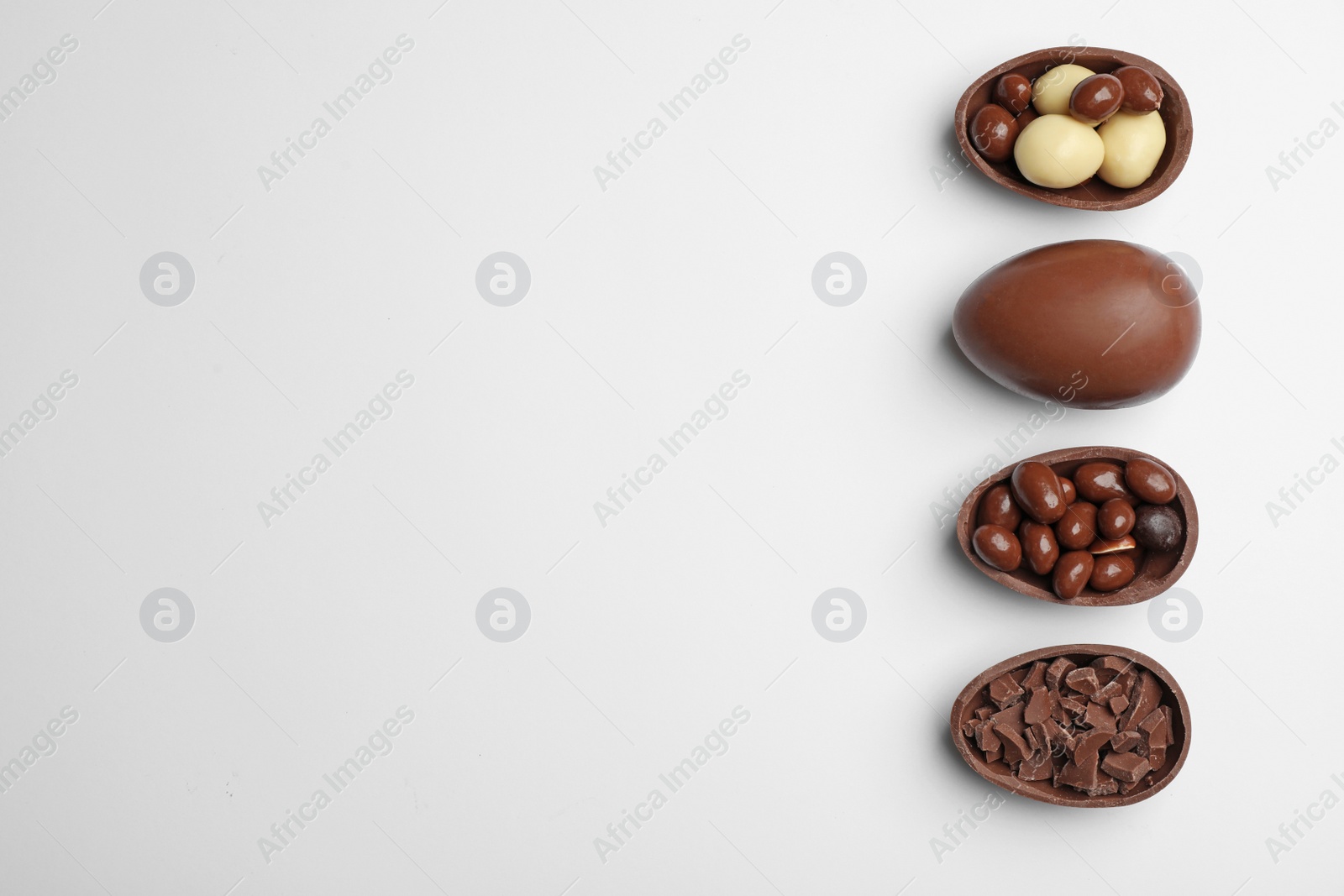 Photo of Tasty chocolate Easter eggs on white background, top view with space for text