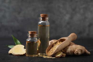 Glass bottles of essential oil, ginger powder and root on dark table