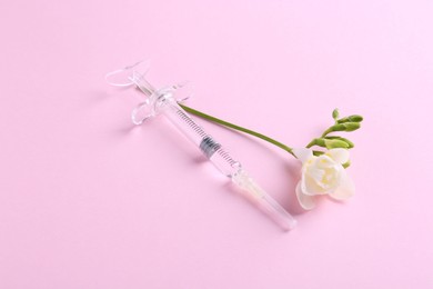 Photo of Cosmetology. Medical syringe and freesia flower on pink background