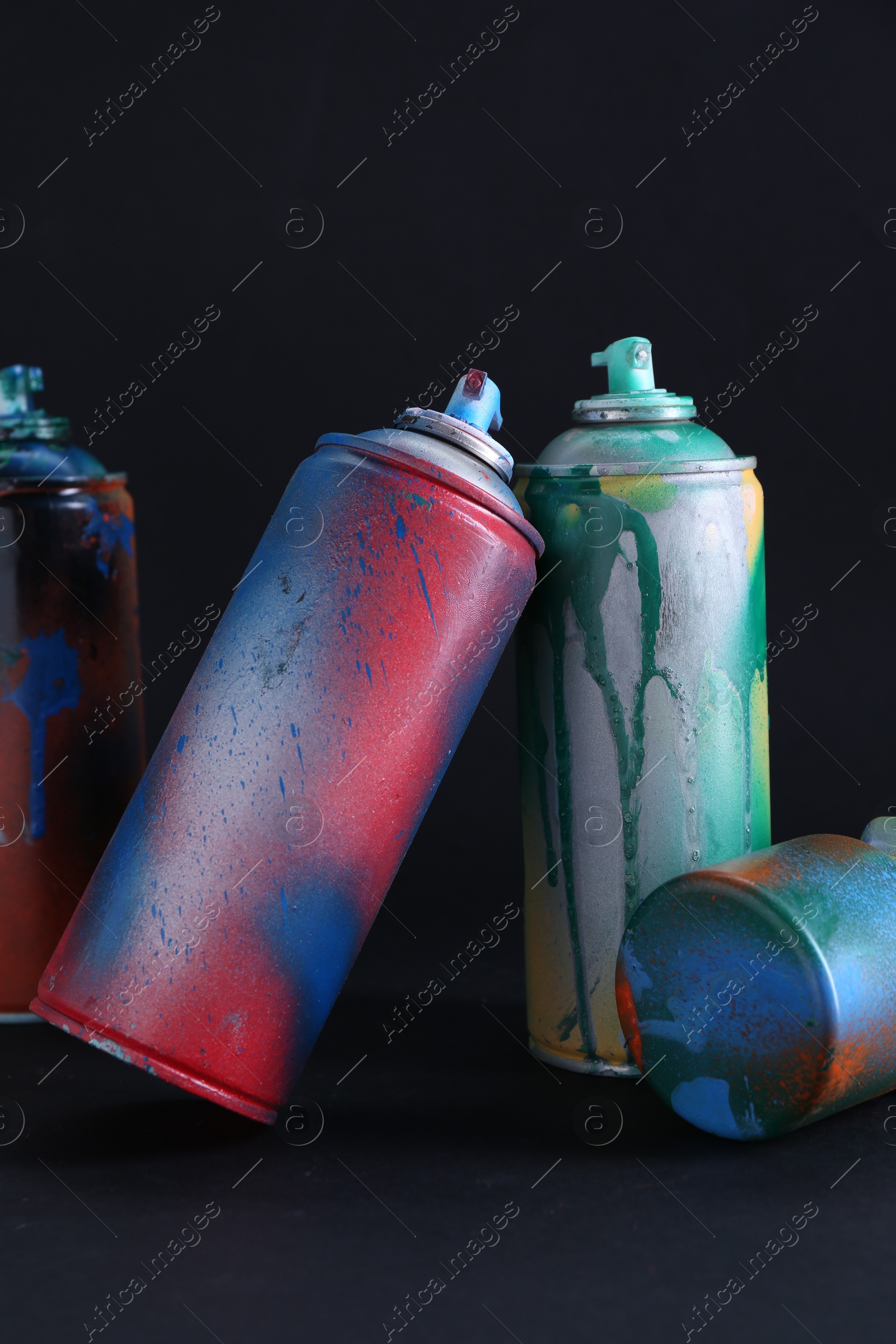 Photo of Many spray paint cans with caps on dark background