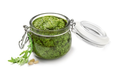 Photo of Jar of tasty arugula pesto and ingredients on white background