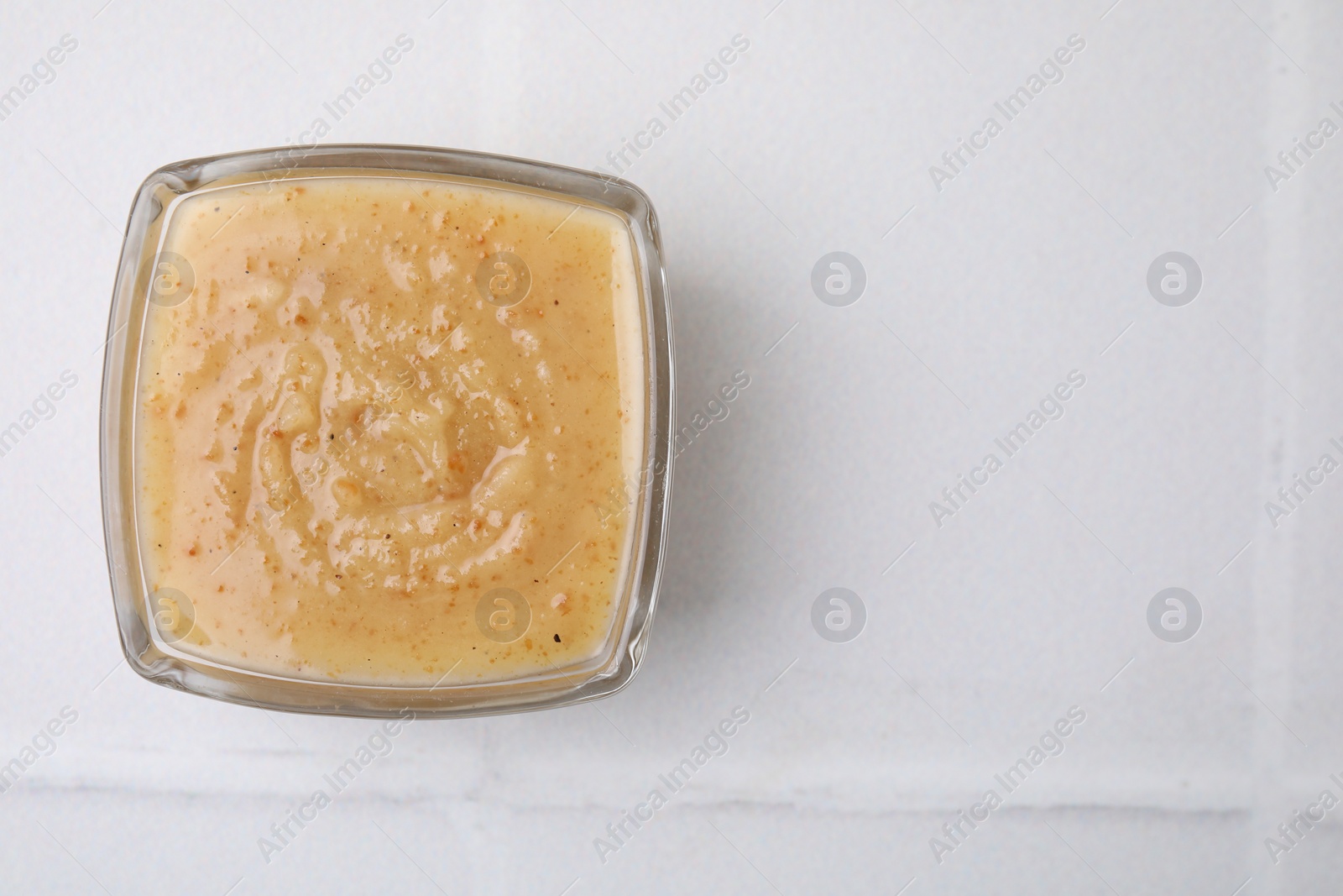 Photo of Delicious turkey gravy on white tiled table, top view. Space for text