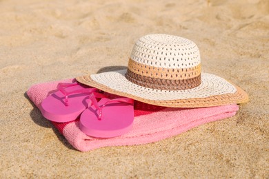 Beach towel with straw hat and slippers on sand