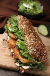 Photo of Delicious sandwich with schnitzel on wooden table, closeup