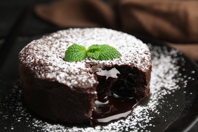 Photo of Delicious fresh fondant with hot chocolate and mint on black plate, closeup