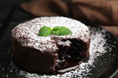 Delicious fresh fondant with hot chocolate and mint on black plate, closeup