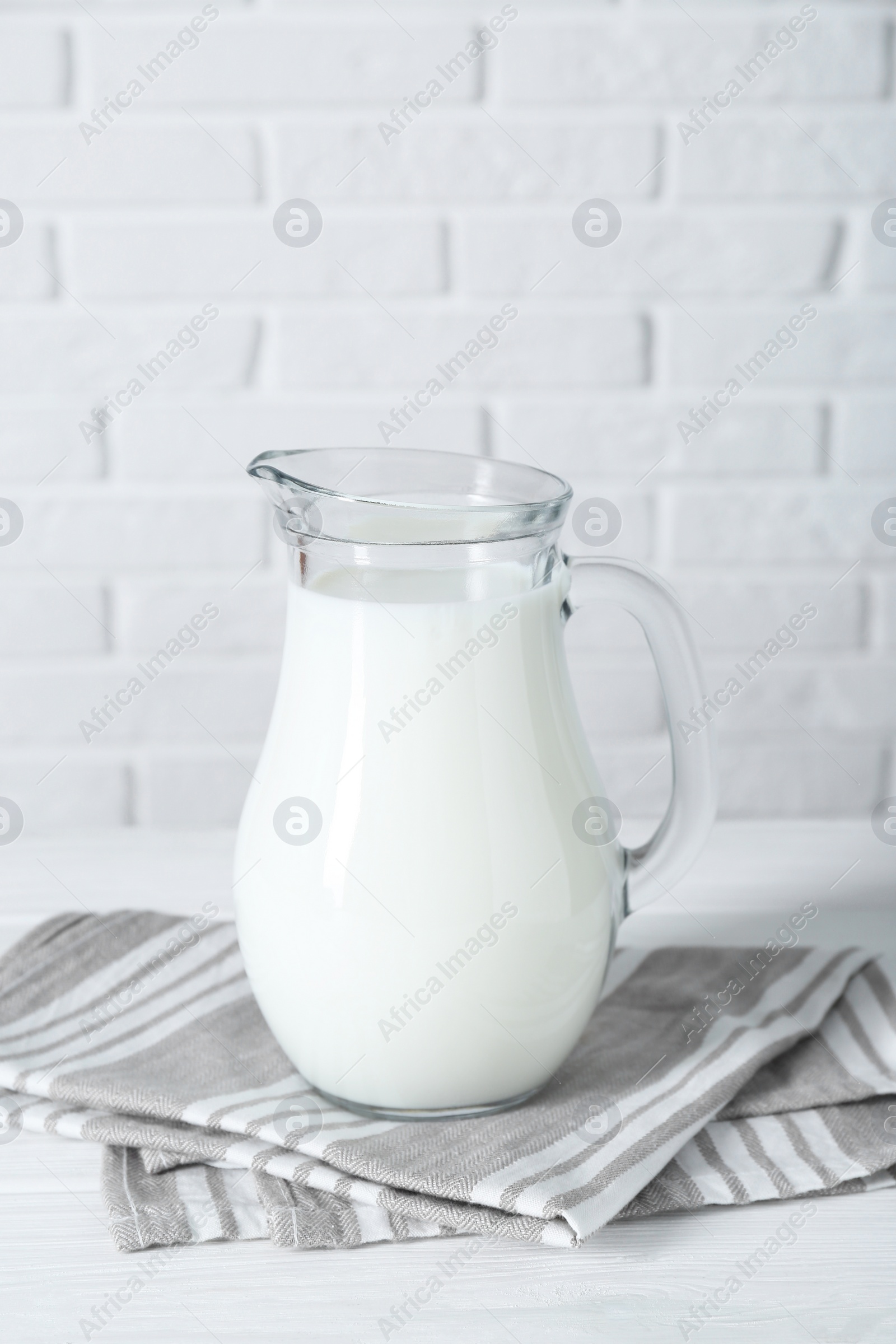 Photo of Jug of fresh milk on white wooden table