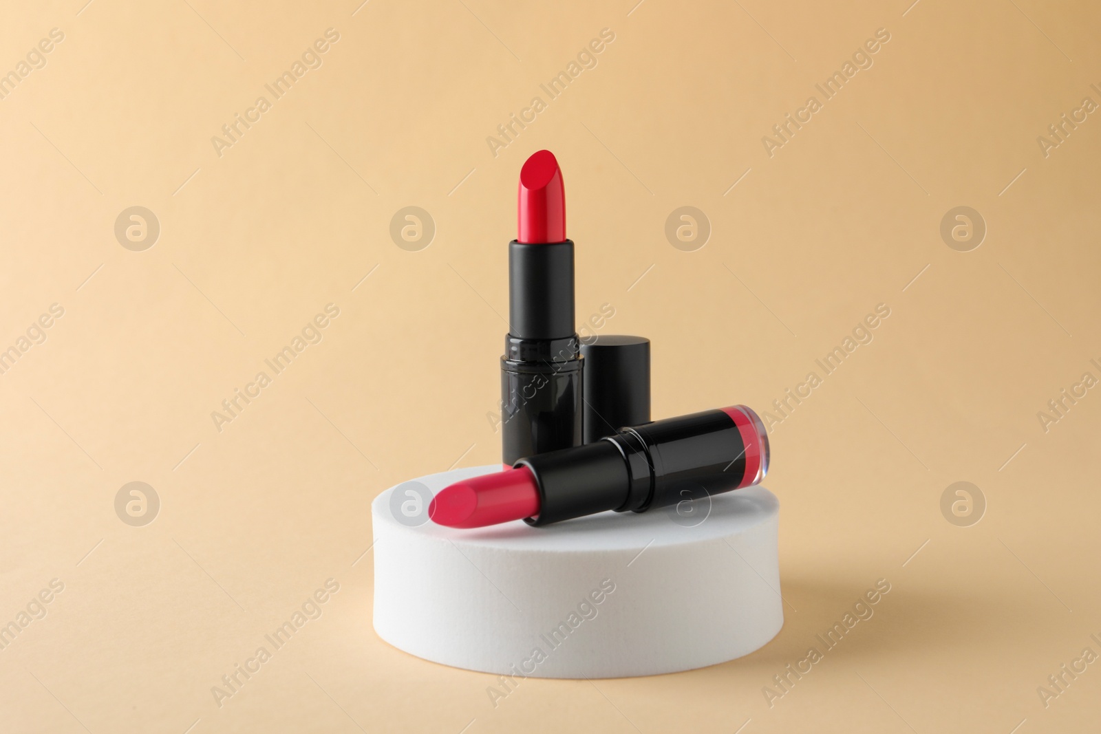 Photo of Beautiful glossy pink lipsticks on beige background