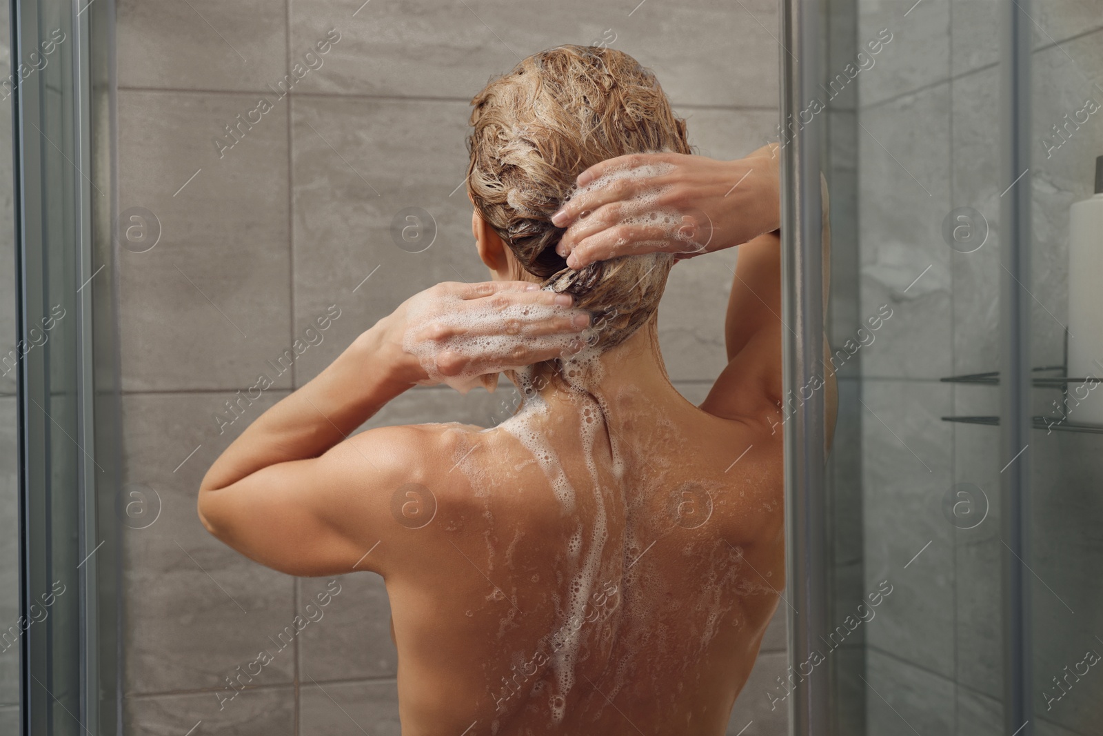 Photo of Woman washing hair in shower stall, back view