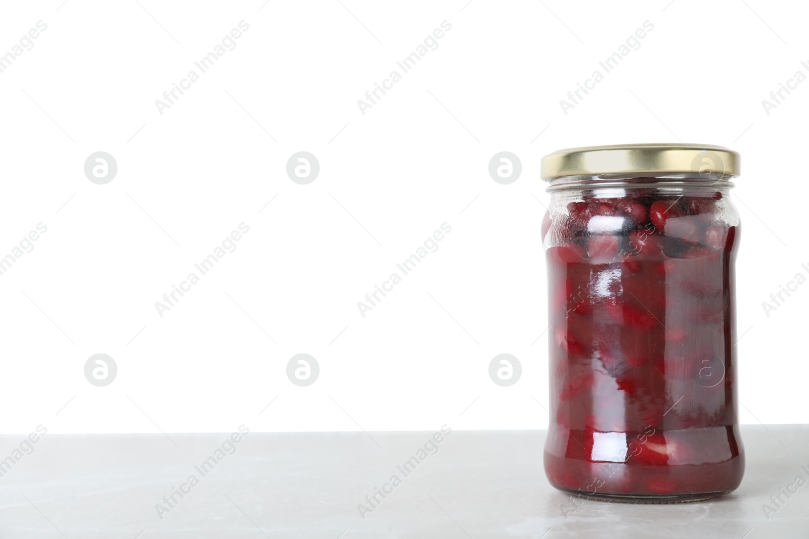 Photo of Glass jar of pickled red beans on light marble table. Space for text