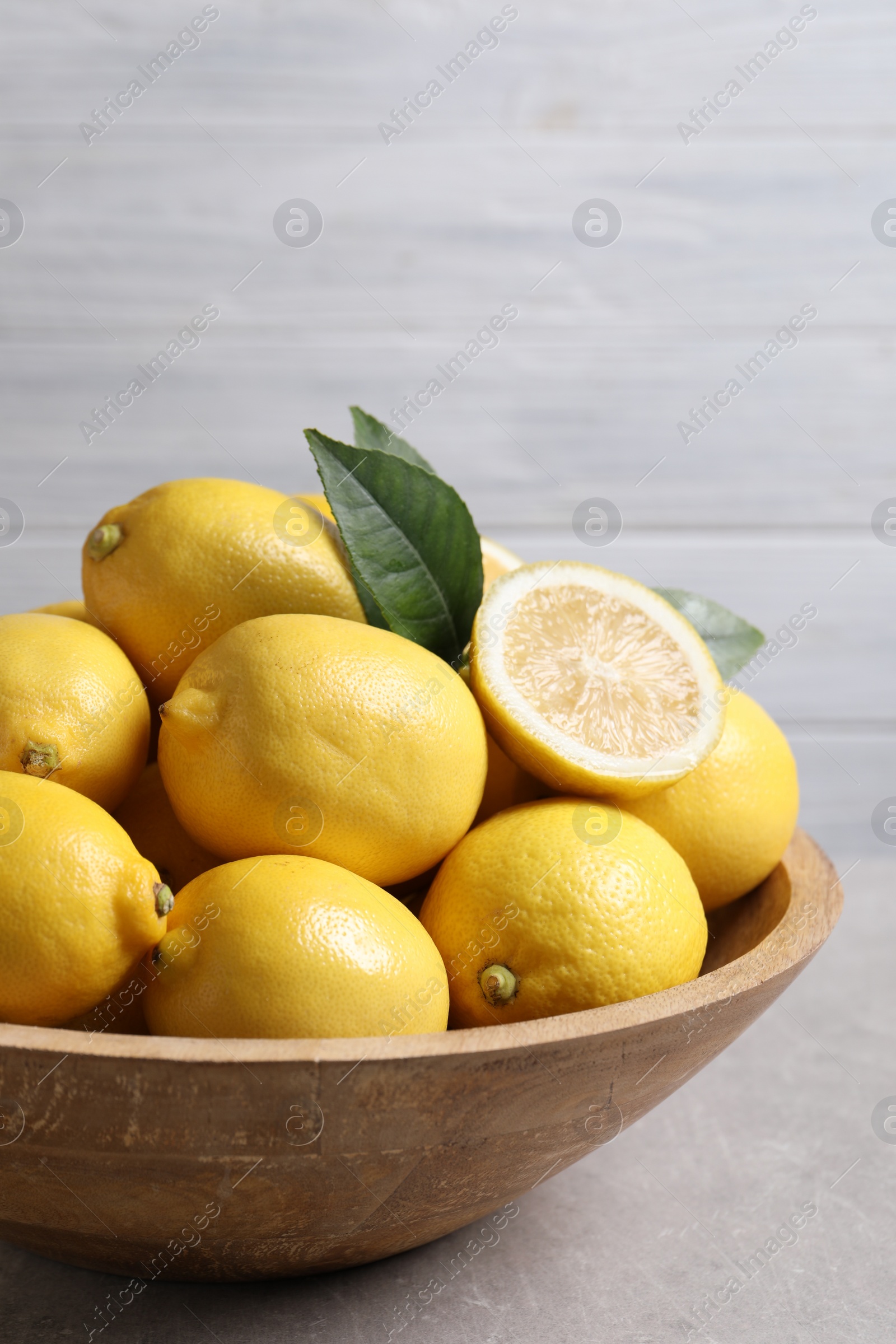 Photo of Many fresh ripe lemons on light grey table