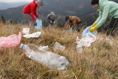 Photo of People collecting garbage in nature, focus on plastic trash