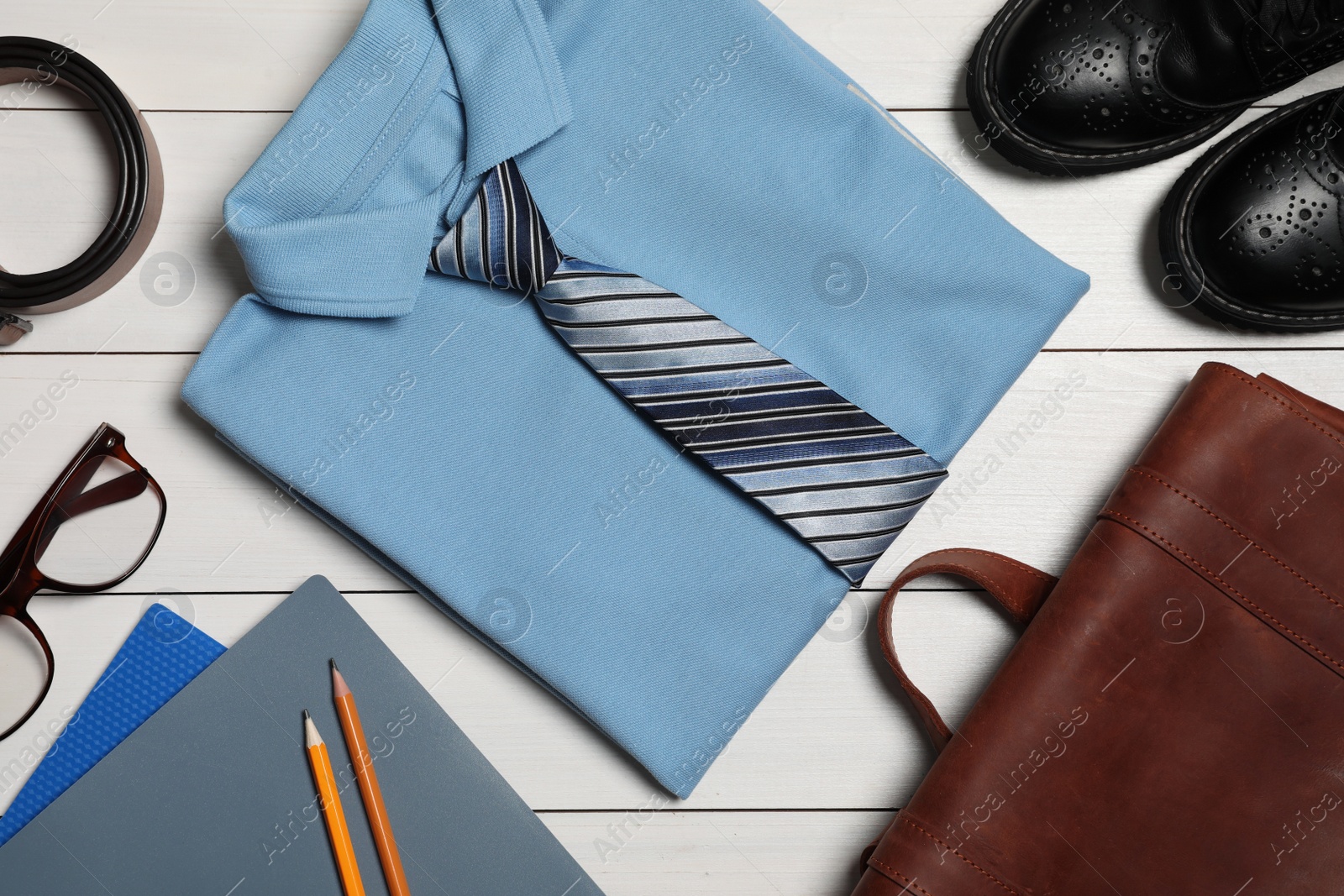 Photo of Stylish school uniform for boy, glasses and stationery on white wooden background, flat lay