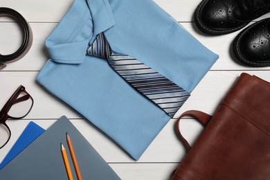 Stylish school uniform for boy, glasses and stationery on white wooden background, flat lay