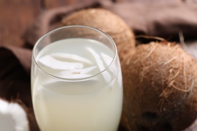 Photo of Glass of coconut water and nuts on table, closeup