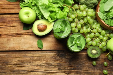 Photo of Green smoothie in glasses and fresh ingredients on wooden table, flat lay. Space for text