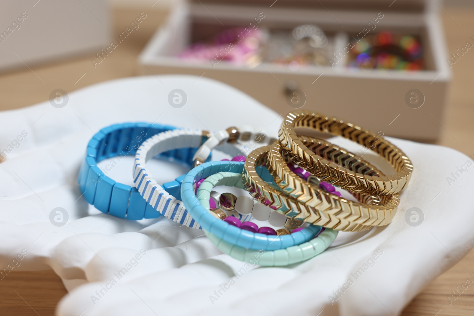 Photo of Ceramic hand stand with many different bracelets on table, closeup