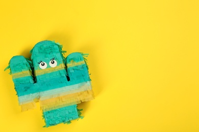 Photo of Bright cactus pinata on yellow background, top view. Space for text