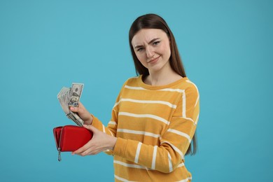 Photo of Woman putting money into wallet on light blue background